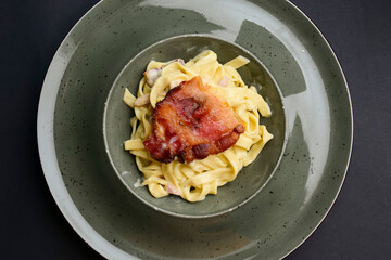 Tagliatelle pasta with steak served in a bowl over black background. Delicious dinner idea.