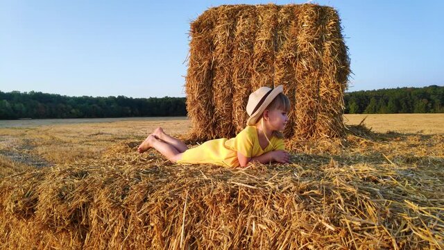 Happy girl lying on haystack