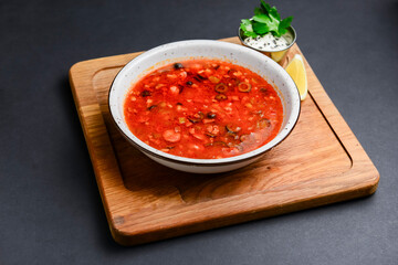 Solyanka rustic style over black background. Traditional Russian recipe, soup solyanka with different kinds of meat.