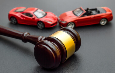 Judge gavel with red toy cars on black.