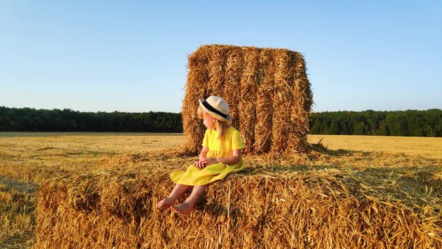 Happy Little girl sitting on haystack and play