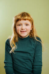 portrait of smiling blonde girl against green background