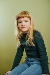 portrait of cute blonde girl against green background