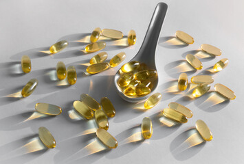 A table spoon full of soft gel vitamins and a handful of vitamins around.