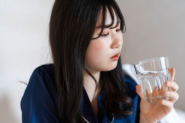 ベッドで水を飲むパジャマの
女性