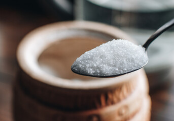 Spoon with sugar on table. Heap of Sugar on vintage wooden background. Sugar bowl.