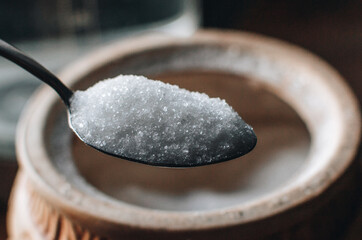 Spoon with sugar on table. Heap of Sugar on vintage wooden background. Sugar bowl.