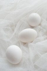 Close up composition of white eggs  on white textured background, top view, copyspace