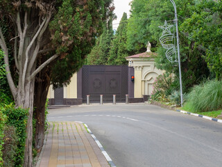 Private railway gate with traffic lights and automatic bollards surrounded by green trees located...