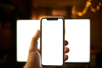 Photo of the white blank screen of the computer and hand holding cellphone. Digital web space...