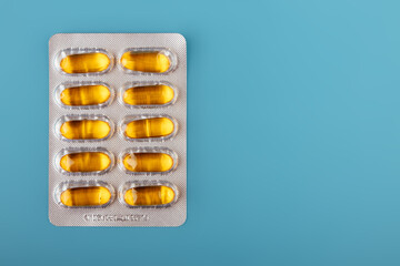 Plate as a package in capsules of vitamin d, fish oil on a blue background. Space for text
