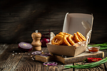 fast food meal onion rings in paper box on wooden table. American food concept. banner, menu, recipe, place for text