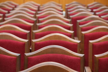 Obraz premium Many red plush chairs with wooden edges stand in rows in the room.Close-up.Selective Focus
