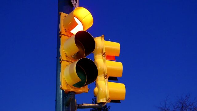 The city traffic light turns from green to red against the blue sky