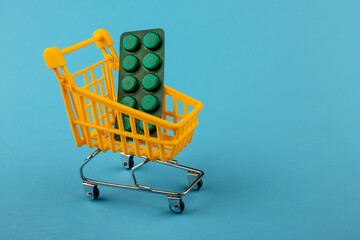 Shopping cart loaded with pills drugs or medicine on yellow background.antibiotics. Women's health, medicine and healthcare concept. Top view, copy space for text.