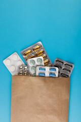 Heap of pills in blister packaging on blue desk. Concept of healthcare, drug addict or chemical weapon. Close-up. 
