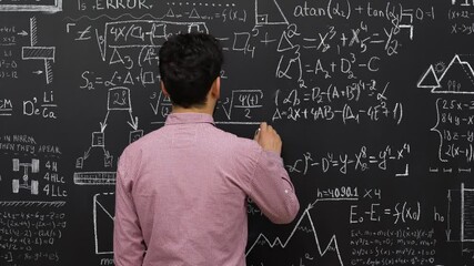 Person writing on blackboard, Back view. Caucasian male lecturer writing math or physics formulas with chalks on blackboard. - Powered by Adobe