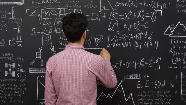 Person writing on blackboard, Back view.   Caucasian male lecturer writing math or physics formulas with chalks on blackboard. 