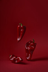 Three red peppers paprika on a red background. Vertical photo