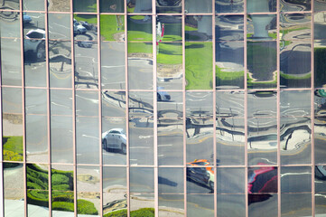 Reflets de voitures, de routes et gazon sur les vitres en miroir d'un gratte-ciel à Dubaï dans un quartier d'affaires au centre-ville.