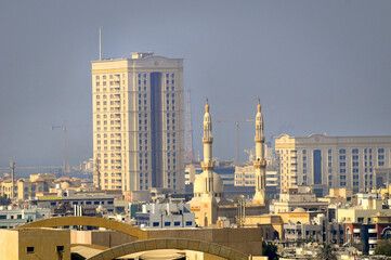 Vue sur les toits, les grattes-ciel et des minarets dans un quartier du centre-ville de Dubaï. Ciel chargé en particules et soleil couchant.