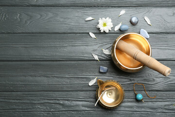 Flat lay composition with golden singing bowl on grey wooden table, space for text. Sound healing