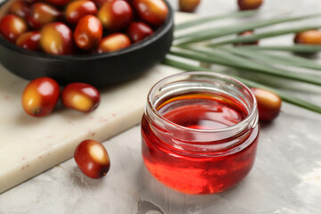 Palm oil in glass jar, tropical leaf and fruits on grey table