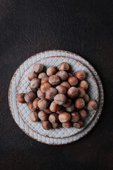Hazelnuts in a ceramic plate on a dark background. Vertical photo.Top view. With copy space