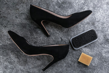 Stylish footwear with shoe care accessories on grey stone table, flat lay