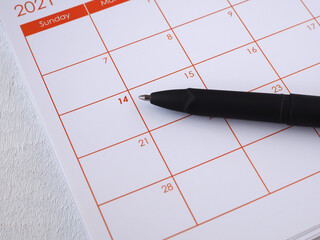 Black pen point to date fourteen, calendar page, the year 2021 on white background. The concept Valentine's Day, anniversary, and wedding. Colse up with copy space for text.