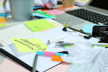 Messy table with laptop and stationery, closeup. Concept of being overwhelmed by work