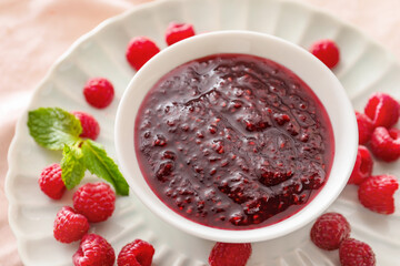 Bowl with sweet raspberry jam on table