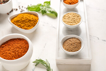 Bowls with different spices on light background