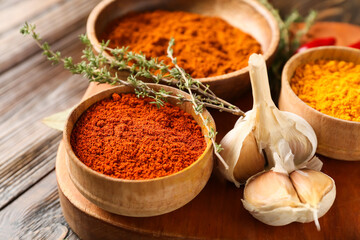Bowls with different spices on wooden background