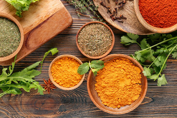 Bowls with different spices and herbs on wooden background