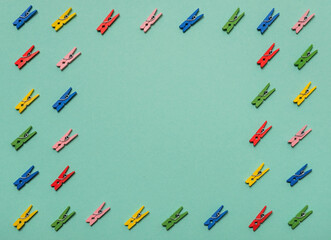 Small wooden clothes pins on colored background with copyspace. Top view