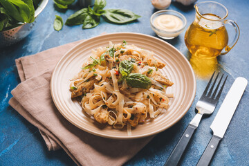 Plate with tasty noodles and chicken on color background