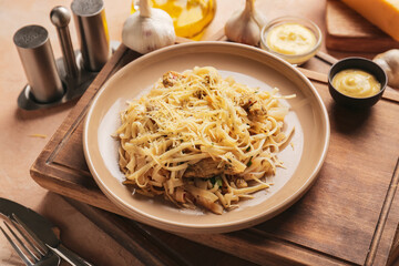 Plate with tasty noodles and chicken on table