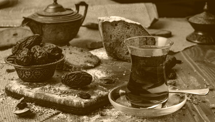 A cup of hot tea with dates on wooden background