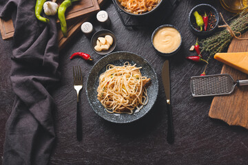 Bowl with tasty noodles and chicken on dark background