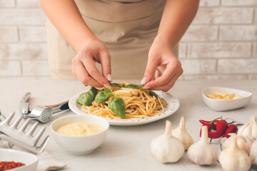Obraz na płótnie Canvas Woman decorating tasty noodles with chicken in kitchen