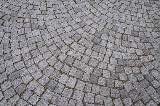Pavimentazione stradale formata da piccoli blocchi di pietra grigi disposti a cerchio