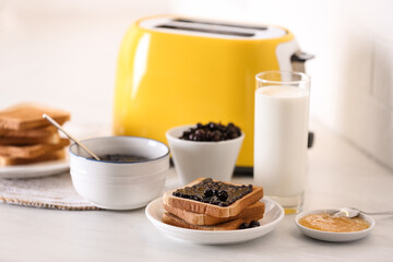 Modern toaster and delicious breakfast on table in kitchen