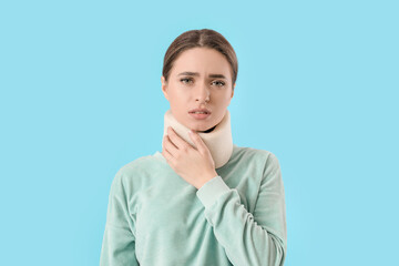 Young woman with cervical collar on neck against color background