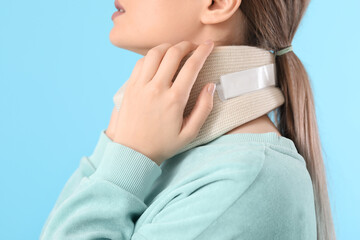 Young woman with cervical collar on neck against color background