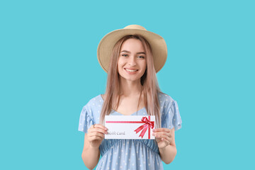 Beautiful young woman with gift card on color background