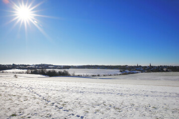 Fototapeta premium the catholic and protestant church of homberg in winter with snow and blue sky and sun 