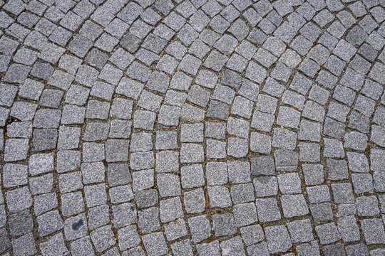 Pavimentazione stradale formata da piccoli blocchi di pietra grigi disposti a cerchio