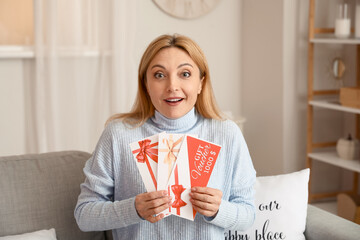 Mature woman with gift cards at home