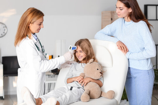 Pediatrician Measuring Temperature Of Little Girl In Clinic